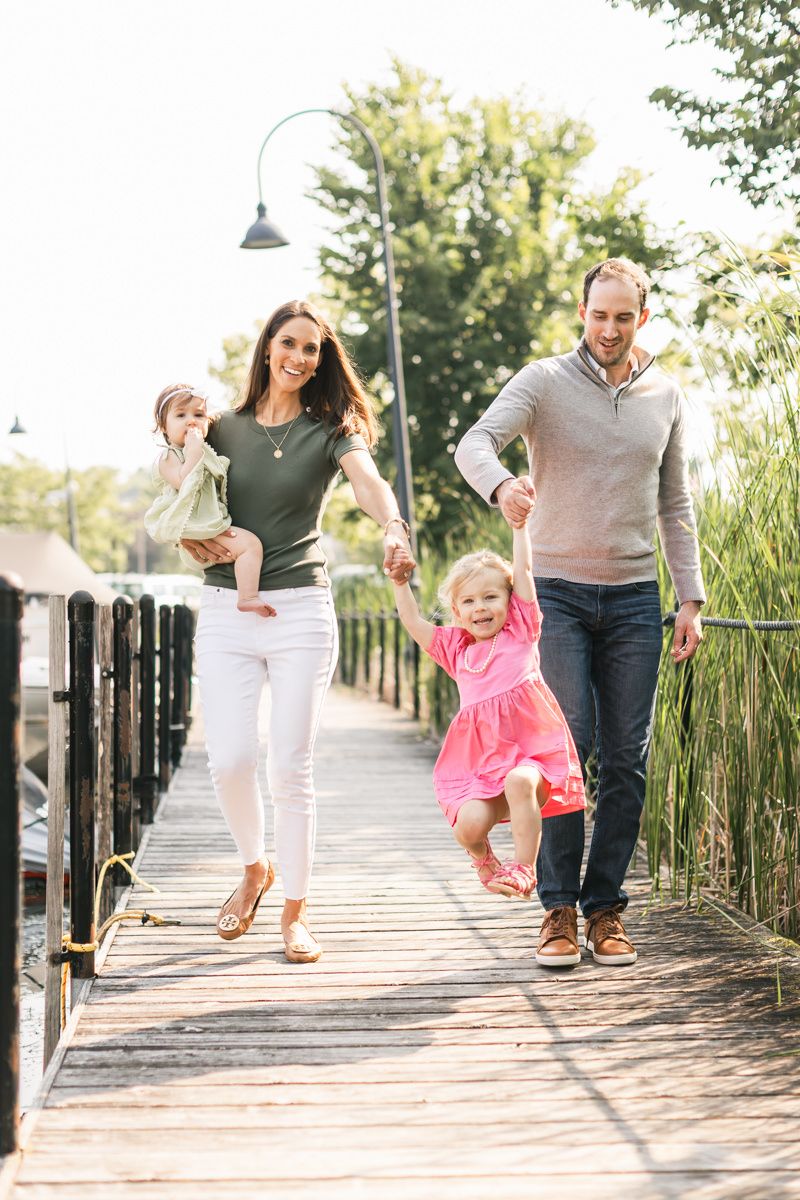 Family walking and playing together on wooden boardwalk in park.
