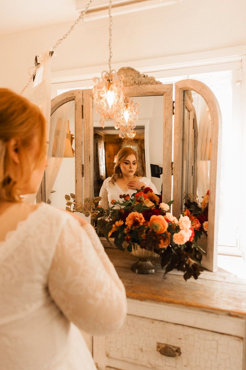 Vintage-style mirror reflections in a romantic setting with warm lighting and floral arrangements create an ethereal atmosphere.