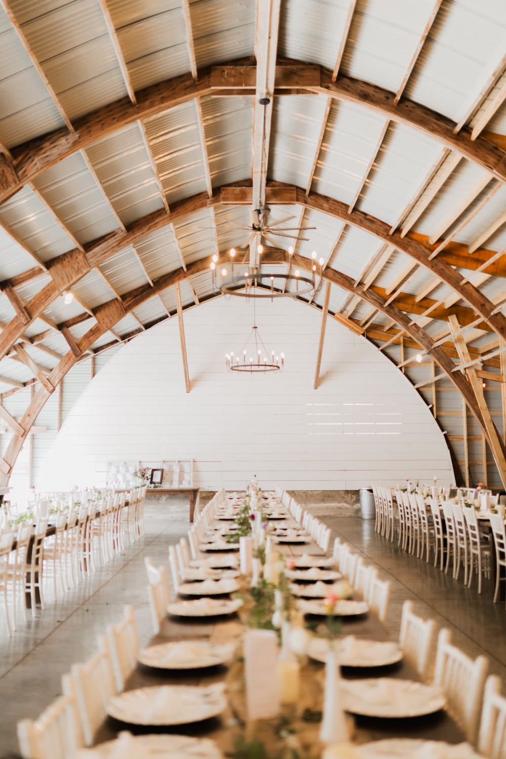 Rustic barn wedding reception venue with exposed wooden beams and long tables set for an elegant celebration.