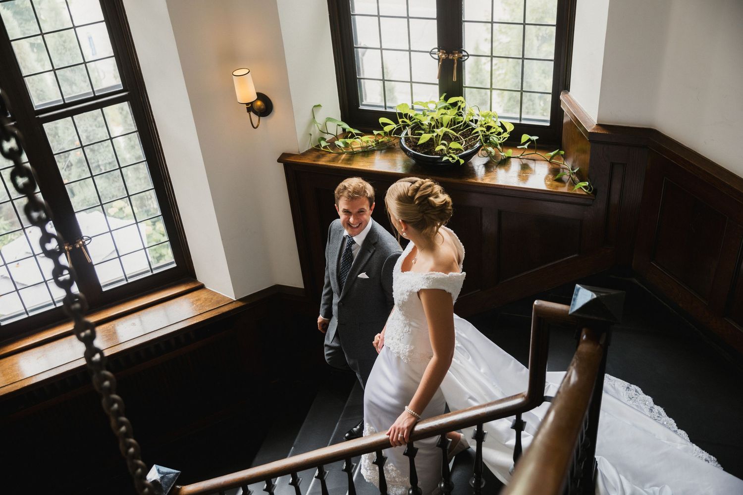 Bride and groom share romantic moment on grand staircase in elegant historic wedding venue.