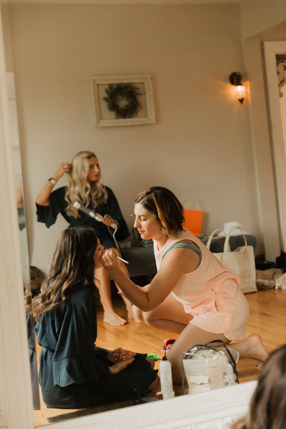 Wedding party getting ready in a bright room with people sitting and styling hair.