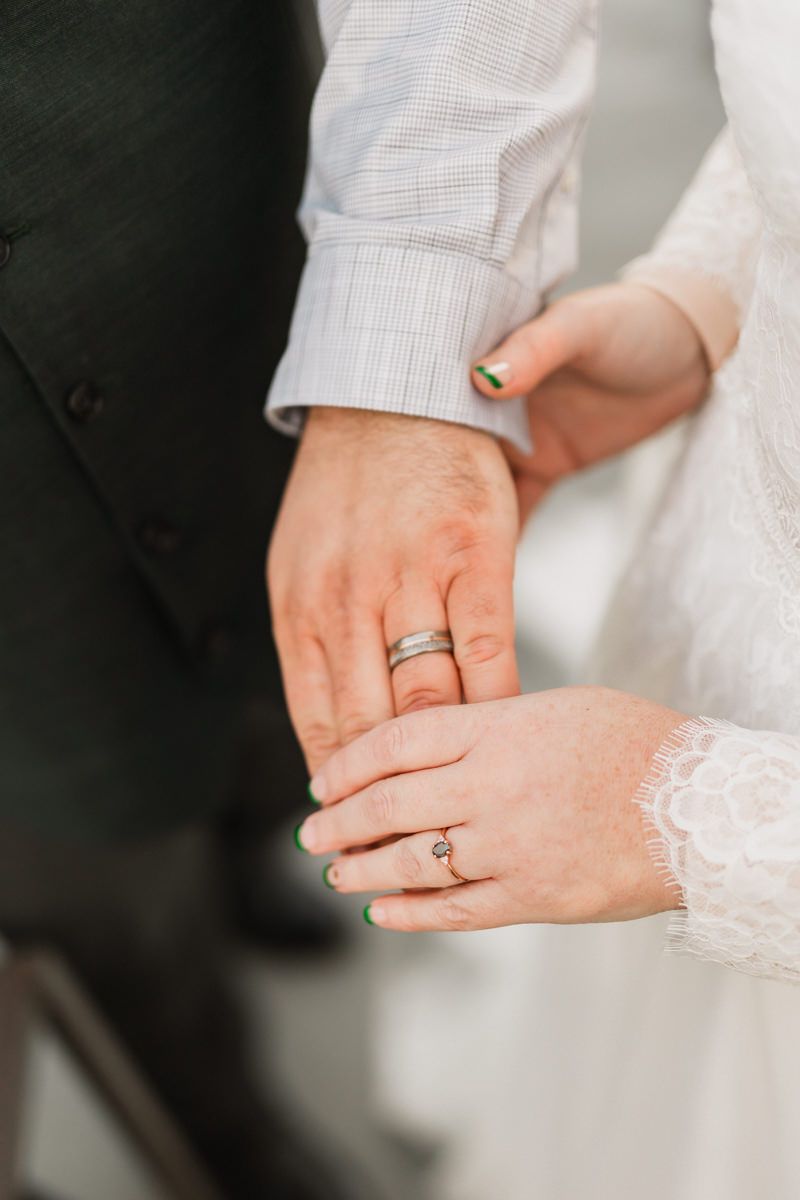 Close-up shots of hands displaying wedding rings against white lace fabric.