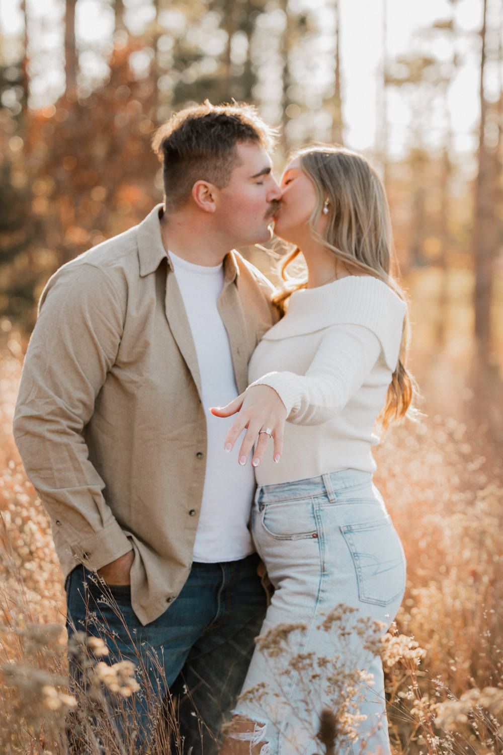Couple sharing intimate moments in a golden field during sunset with warm autumn colors.