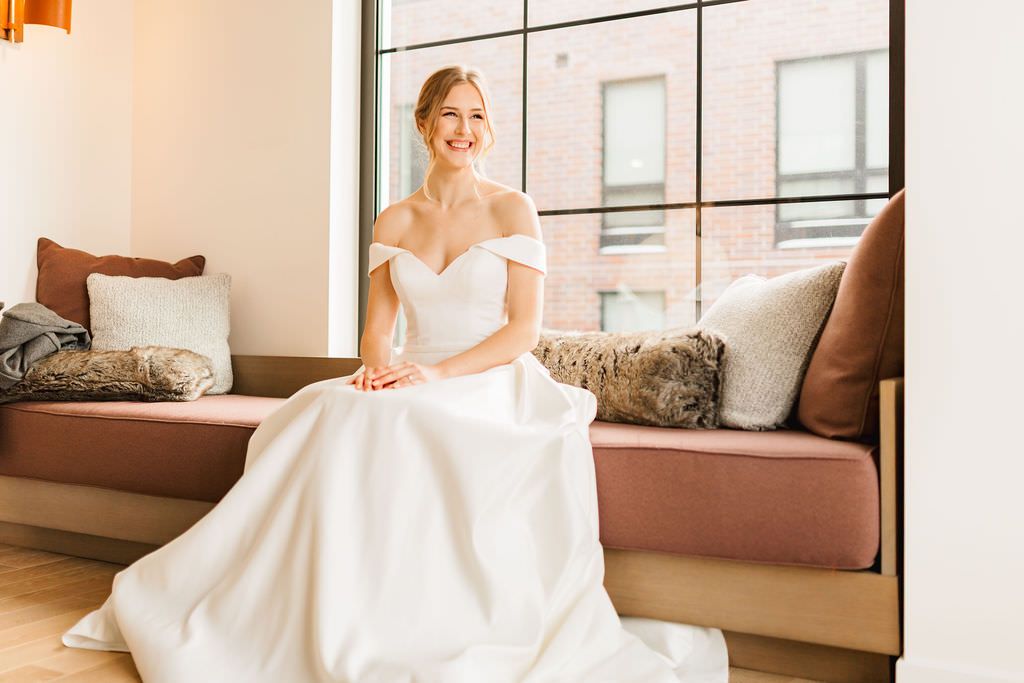 An elegant wedding gown with a full ballgown skirt is showcased in a modern interior setting.