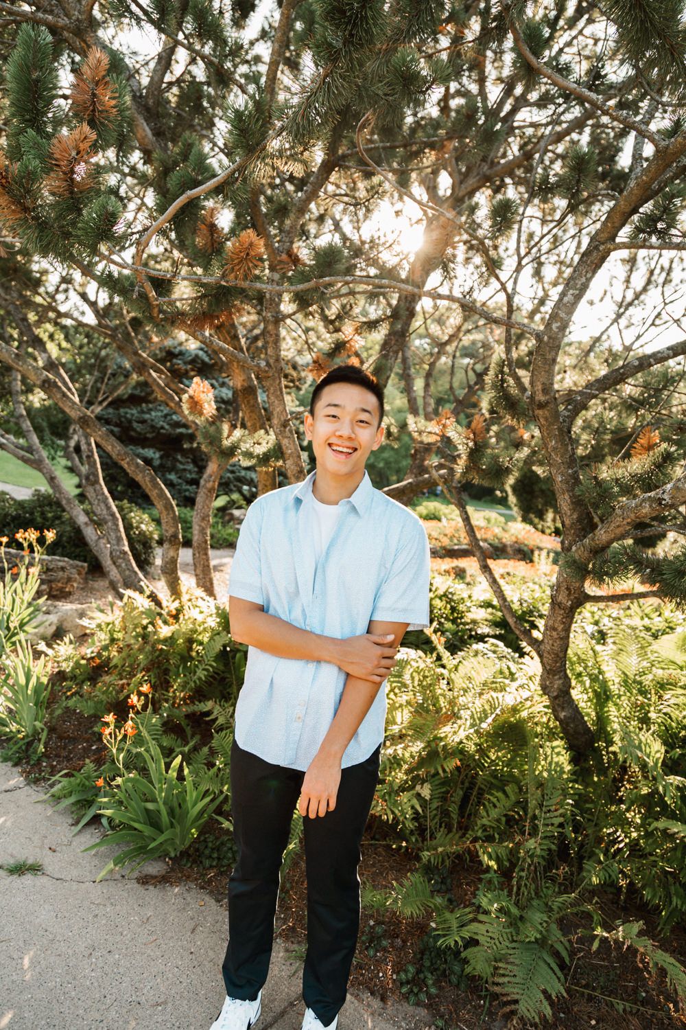 Natural outdoor portrait under trees with sunshine filtering through branches.