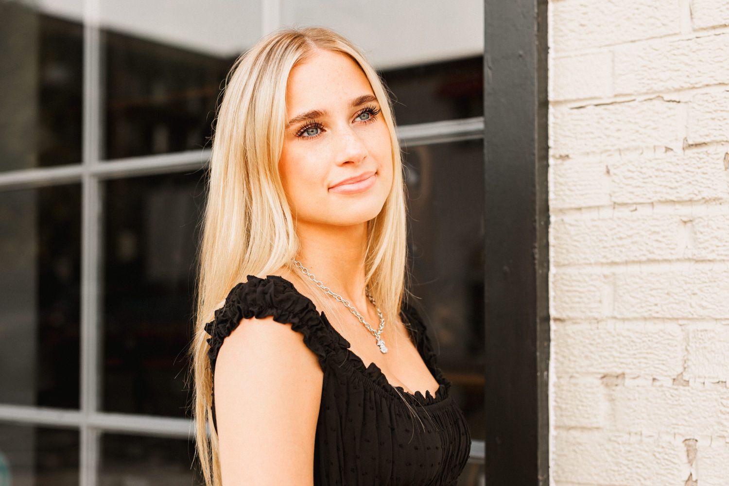 Casual outdoor fashion photo against white brick wall showing summer style.