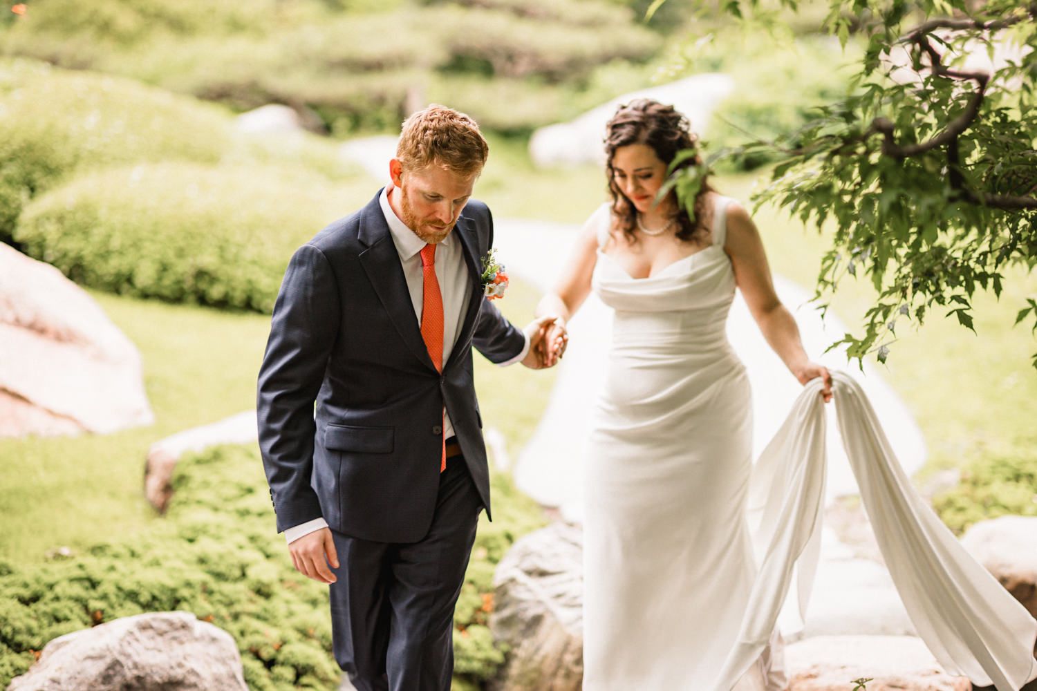 Candid wedding moments captured in a sunlit garden pathway.