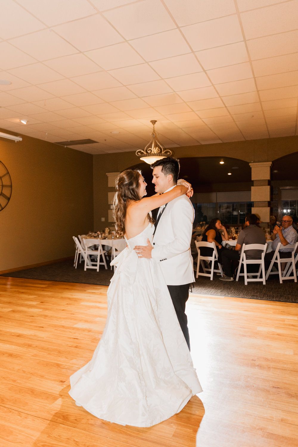 First dance on a polished wooden ballroom floor at an elegant wedding reception.