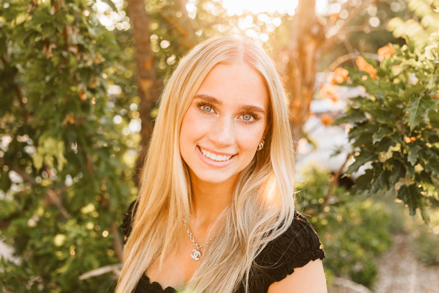 Portrait shot in natural lighting with green foliage background and golden sunlight.