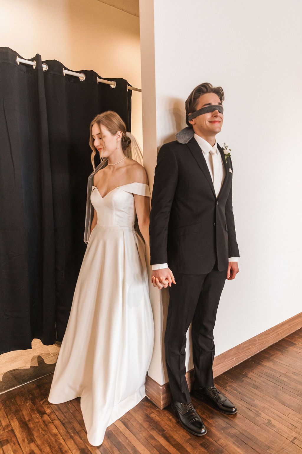 Couple sharing an intimate first look moment in a hallway before their wedding ceremony.