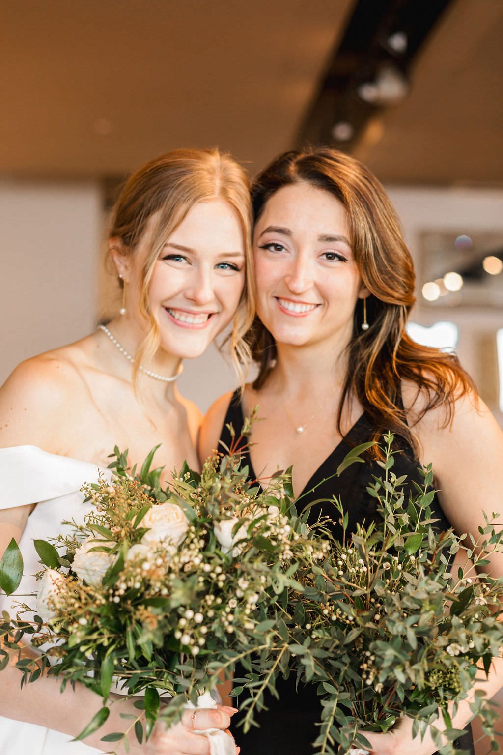 Two people holding lush greenery bouquets with white flowers and eucalyptus.