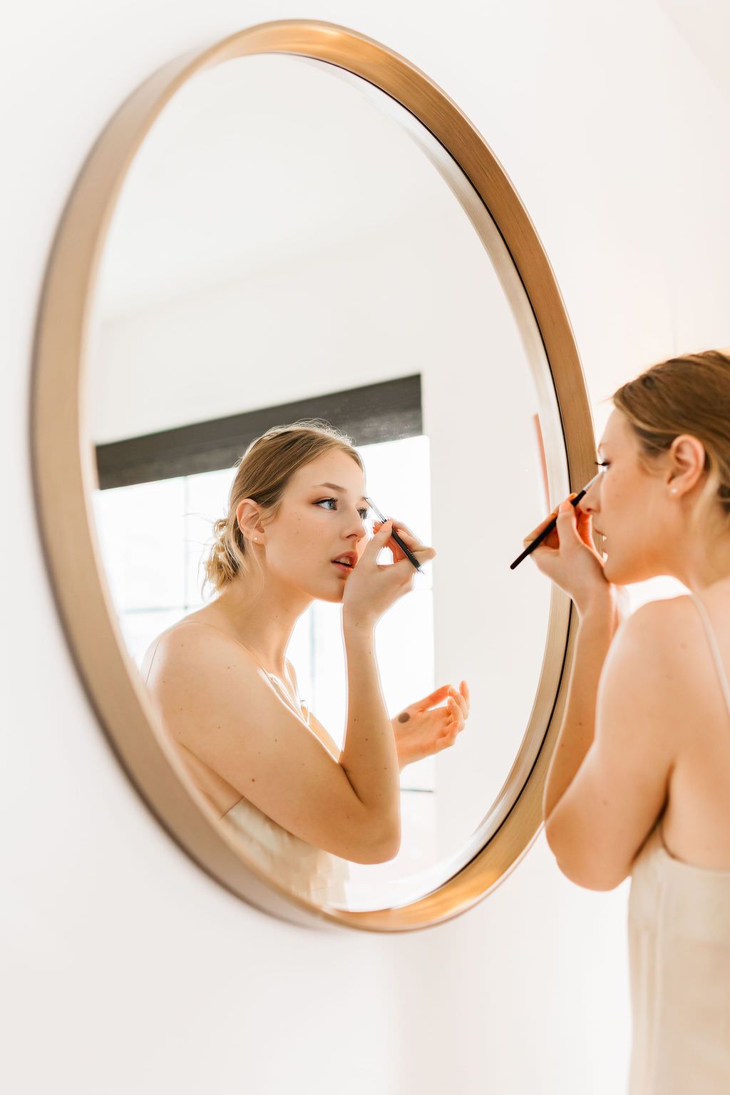 A creative composition of four circular mirrors showing split views of a person applying makeup in an elegant setting.