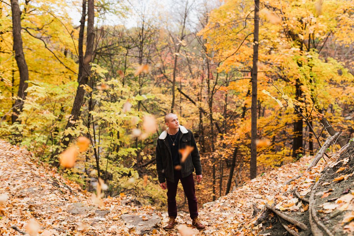 Person in black clothing hiking through forest with vibrant fall colors.