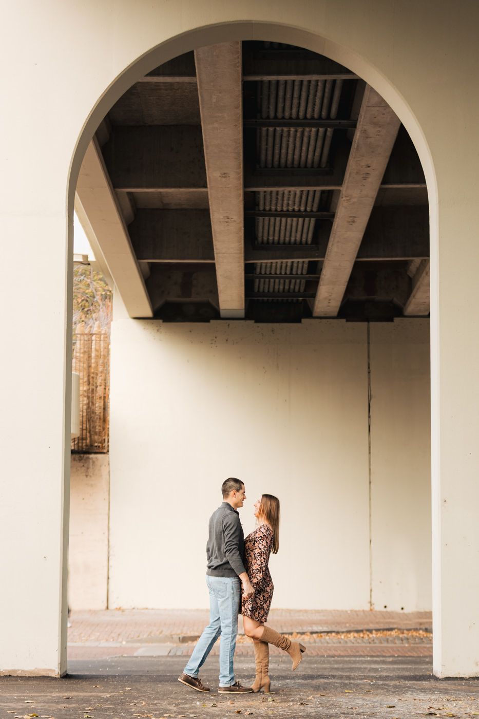 A couple sharing a romantic moment under an architectural archway.
