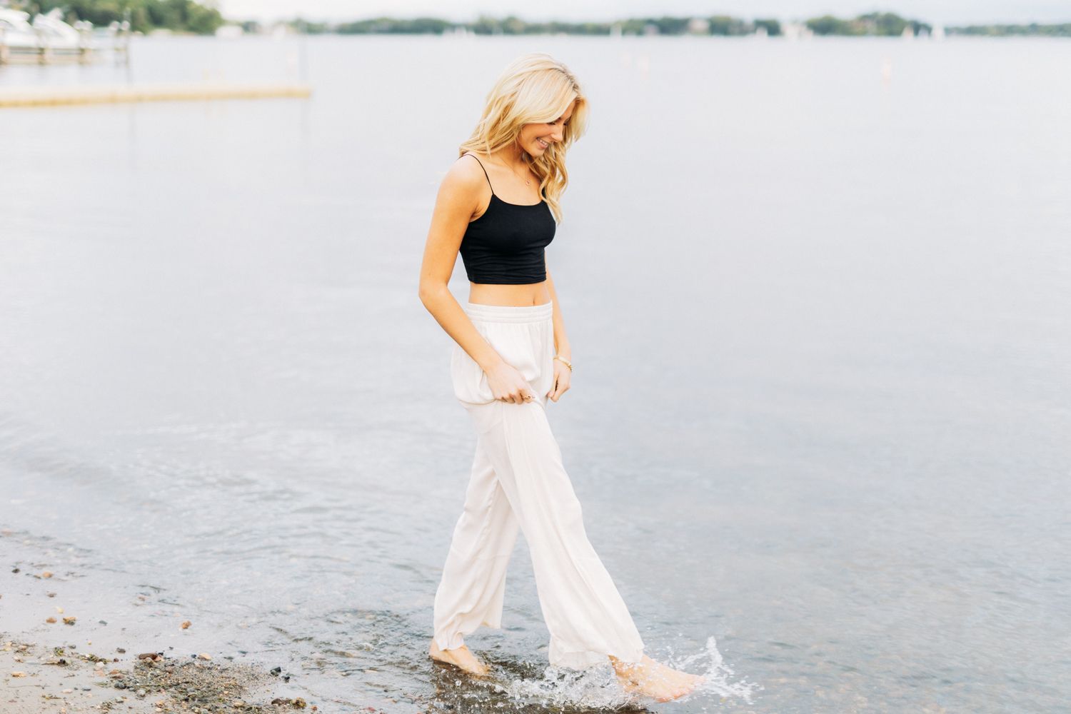 Long exposure photo showing movement as someone strolls by the water's edge in flowy white clothing.
