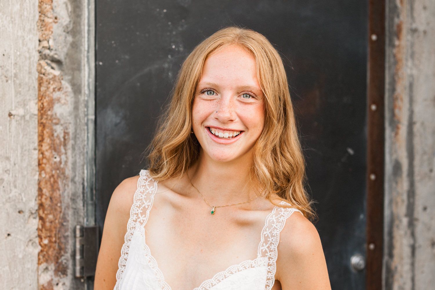Portrait against a dark backdrop showcasing a white summer top and natural wavy hair.