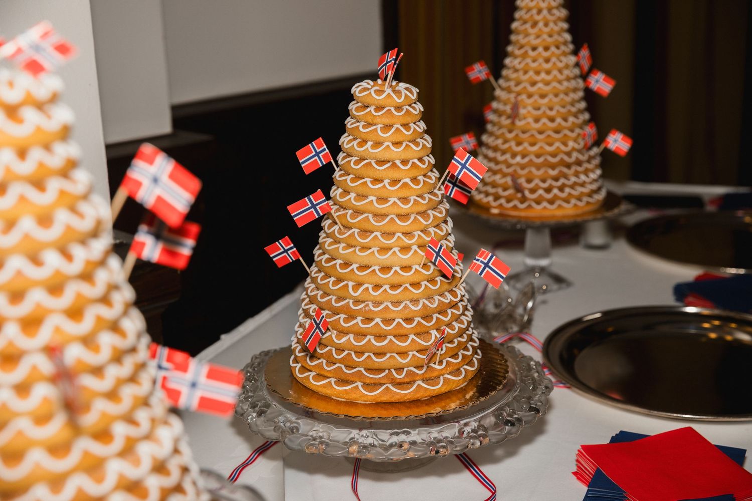 Traditional Norwegian Kransekake tower cake decorated with Norwegian flags on a festive table.