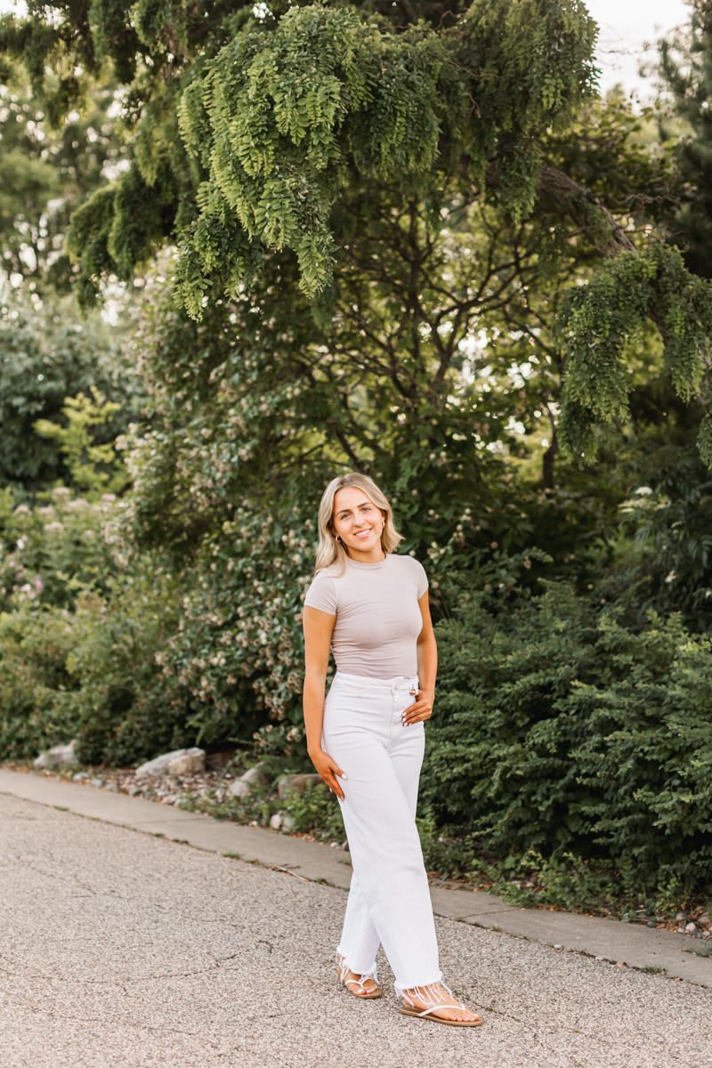 Casual outdoor portrait session on a gravel path surrounded by lush green trees.