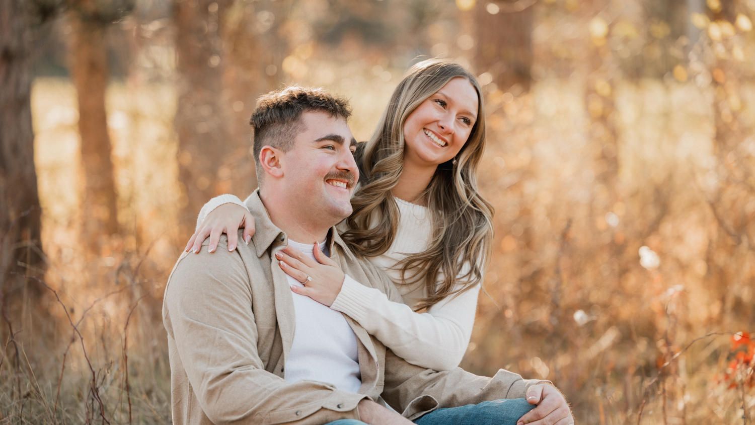 Romantic couple embracing in an autumn field with warm sunlit grass.