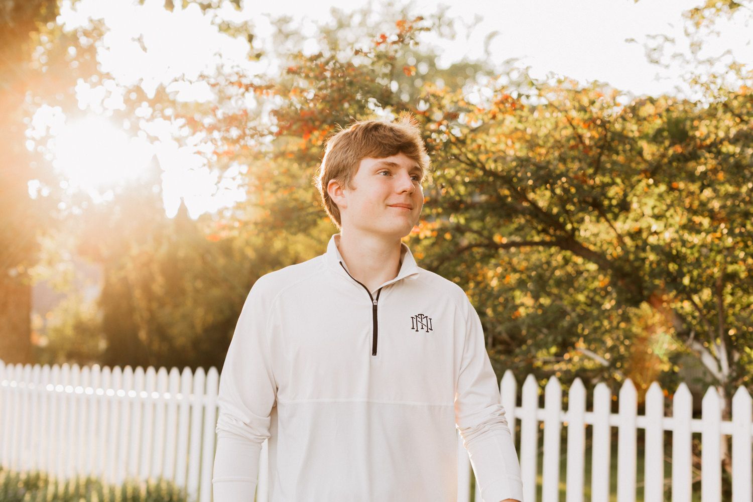 Individual standing outdoors at sunset with warm golden light filtering through trees.