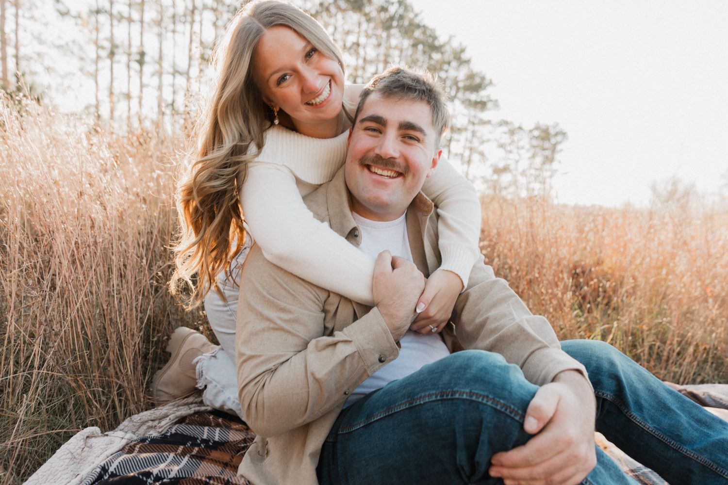 A couple shares joyful laughter while sitting together in nature.