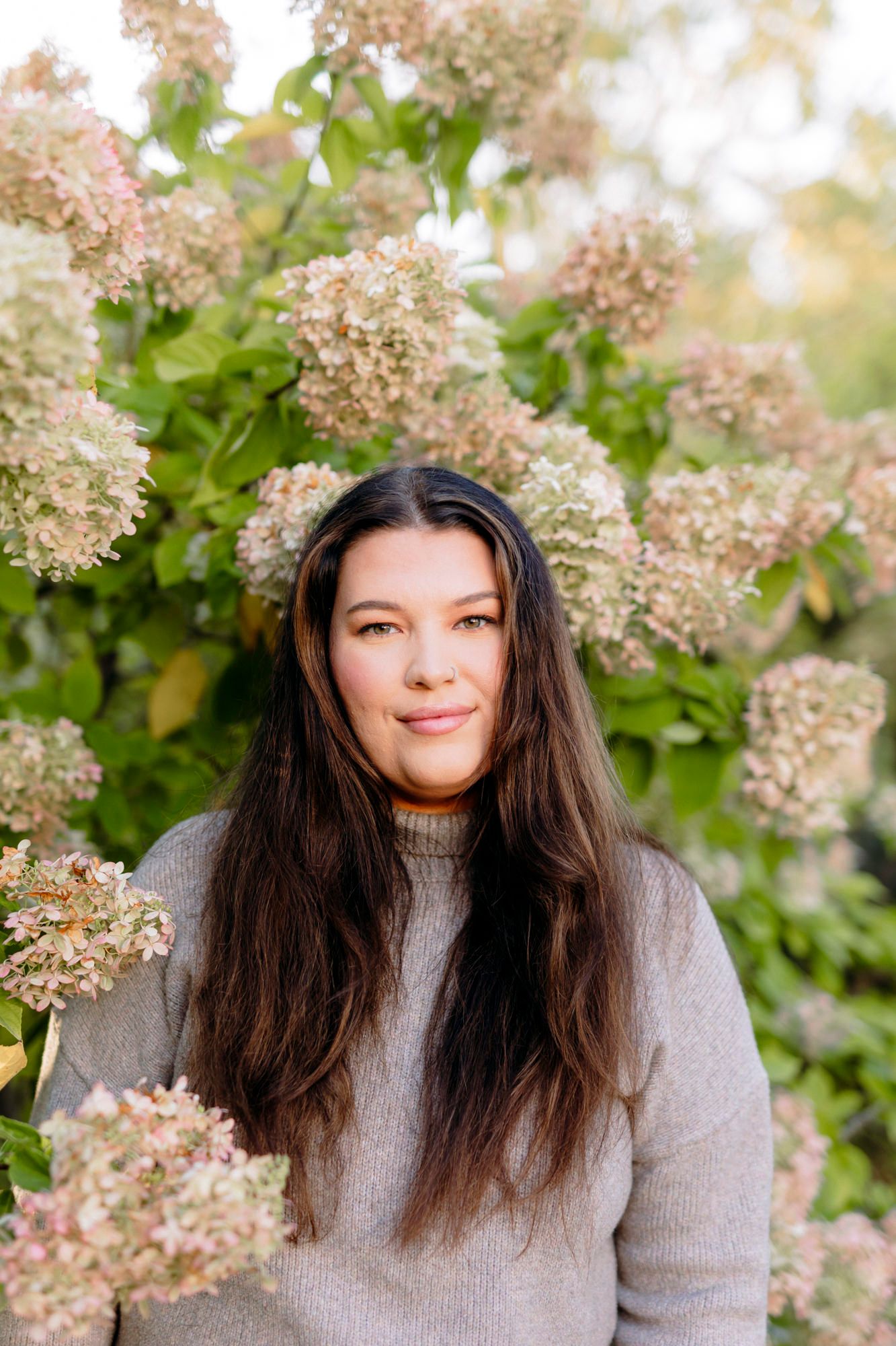 Outdoor portrait with blooming hydrangea flowers in soft natural lighting.