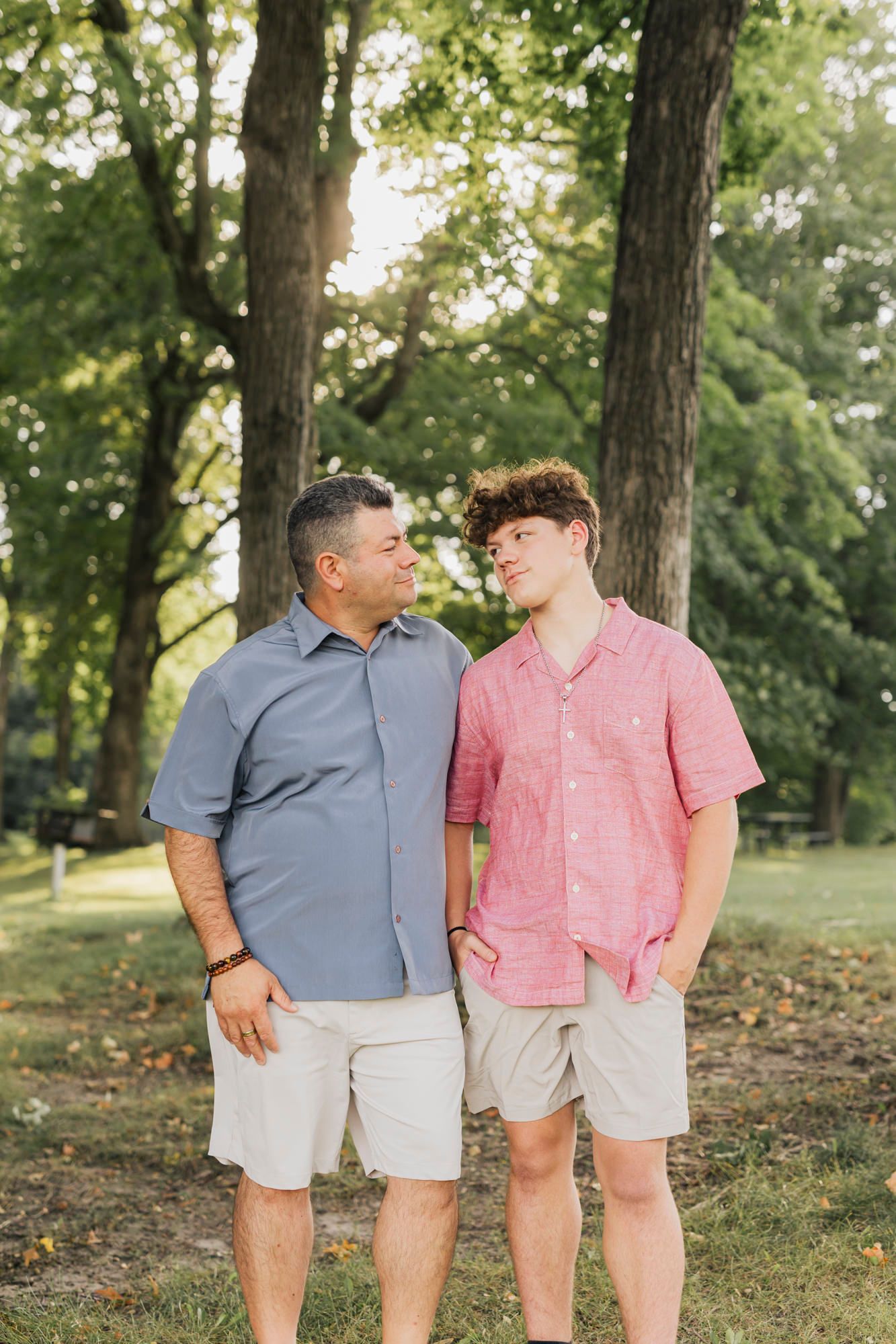 Couple wearing coordinating pink and blue outfits poses together in a park setting.