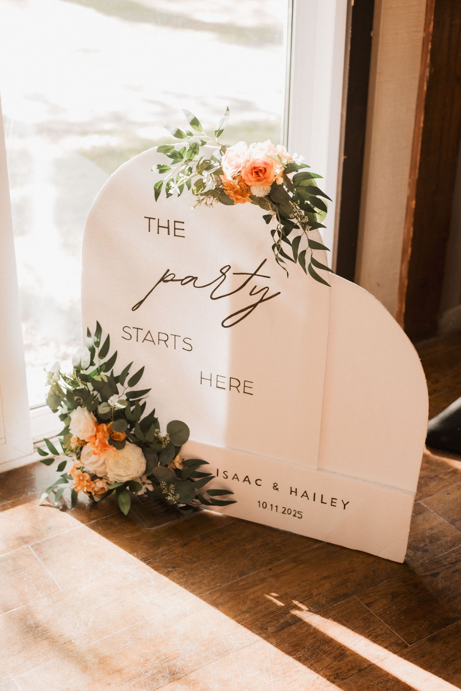 Wedding reception signage with elegant calligraphy and floral accents displayed on a rustic wooden surface.