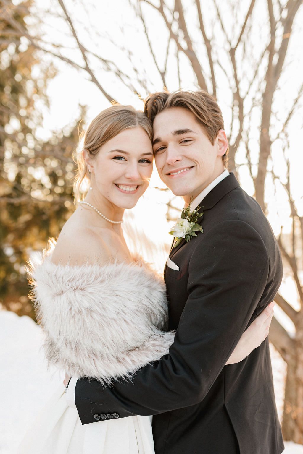 Romantic winter wedding portraits with couple embracing in snowy setting.