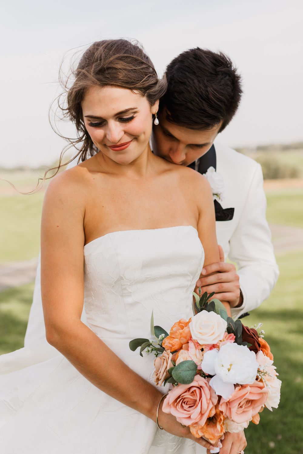 A romantic wedding moment outdoors with a beautiful bouquet of peach and white roses.