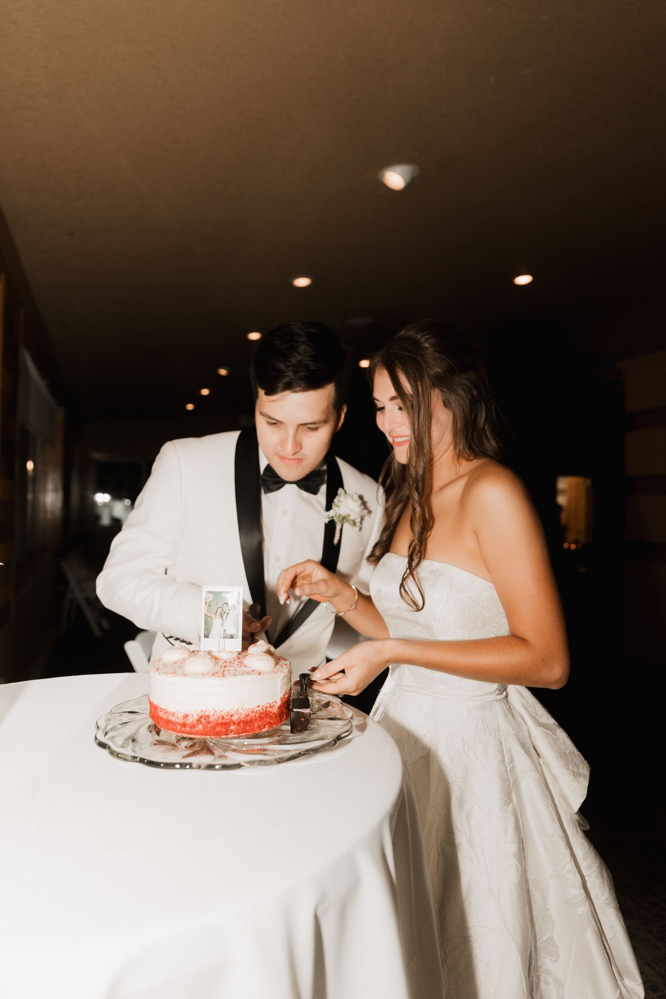 Bride and groom cutting their pink wedding cake together at their elegant evening reception.
