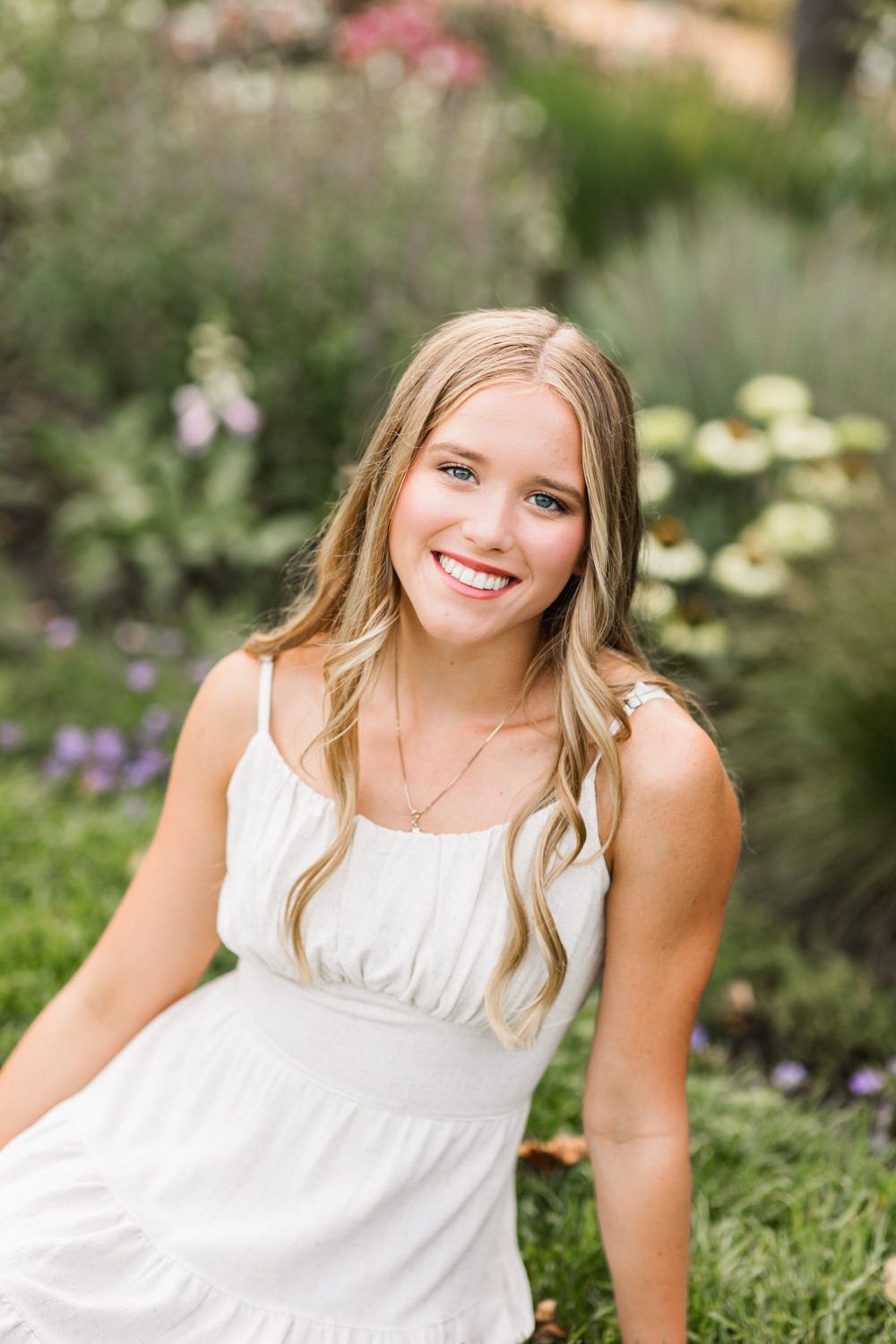 Playful summer portraits captured in a blooming flower garden with soft natural lighting.