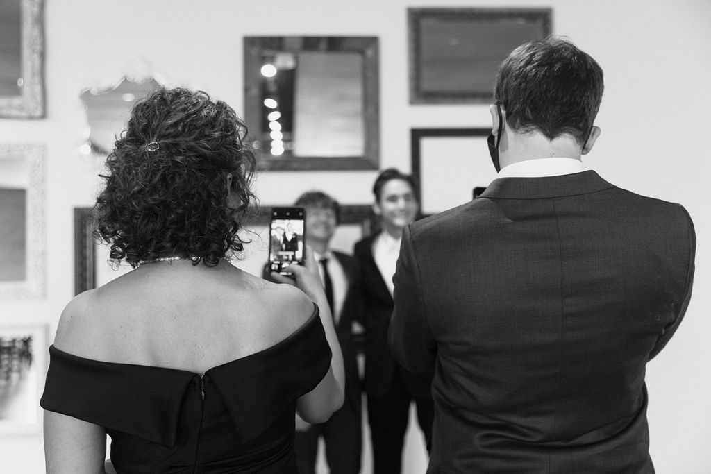 Black and white image of wedding guests taking photos during the celebration.