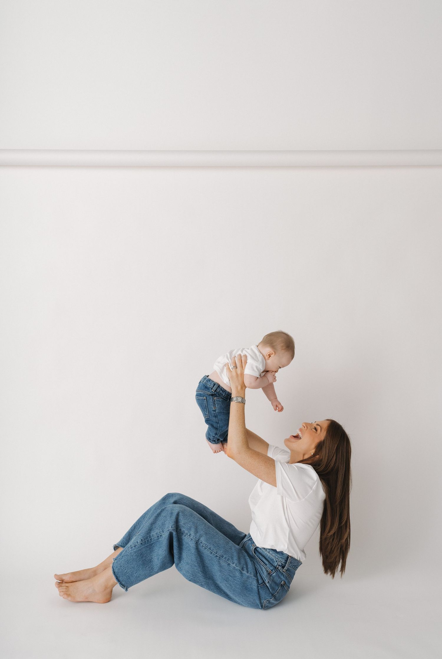 Playful interaction between parent and infant on white floor.