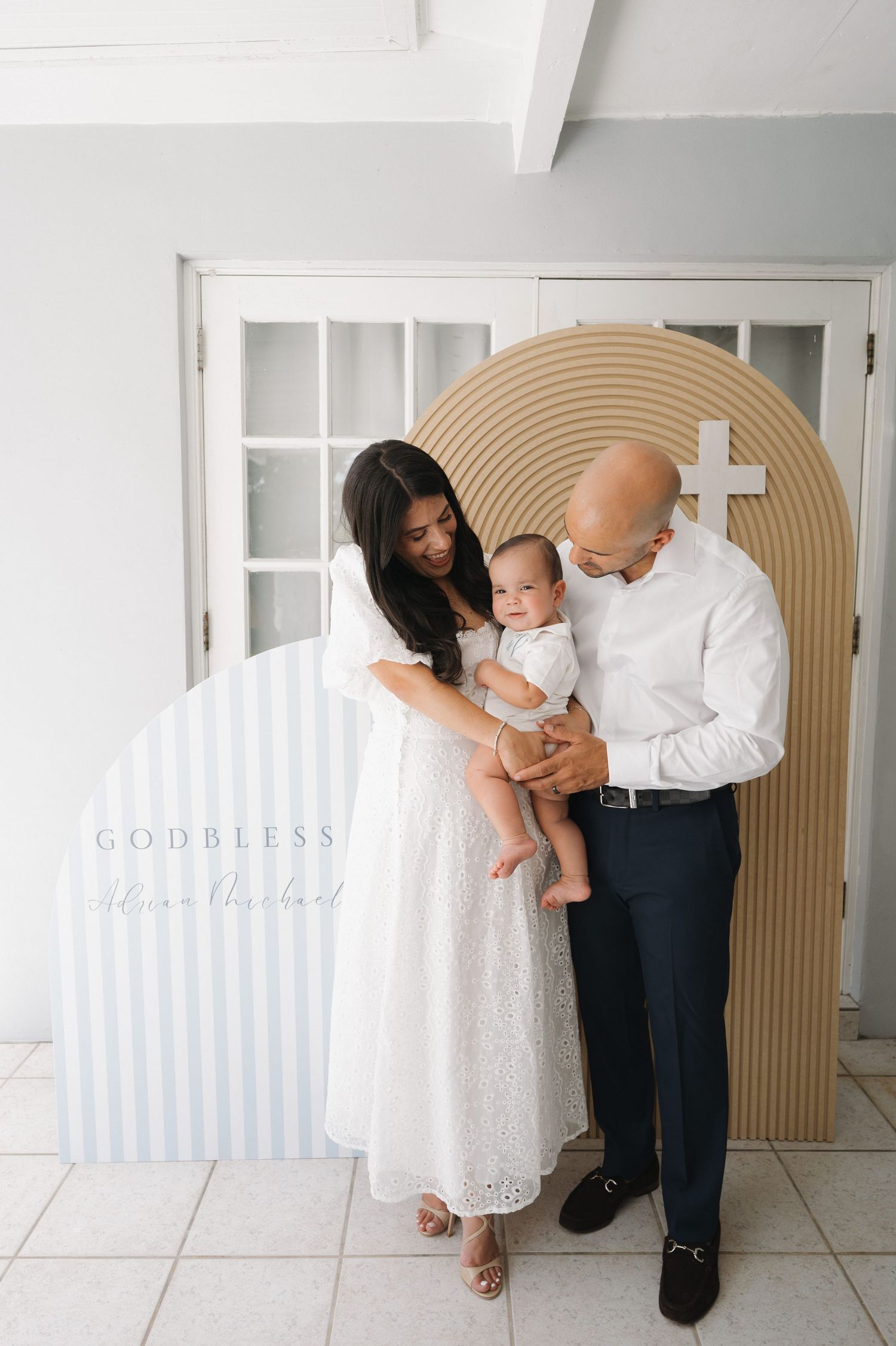 Family portrait session with white and beige color scheme against decorative arch backdrop.