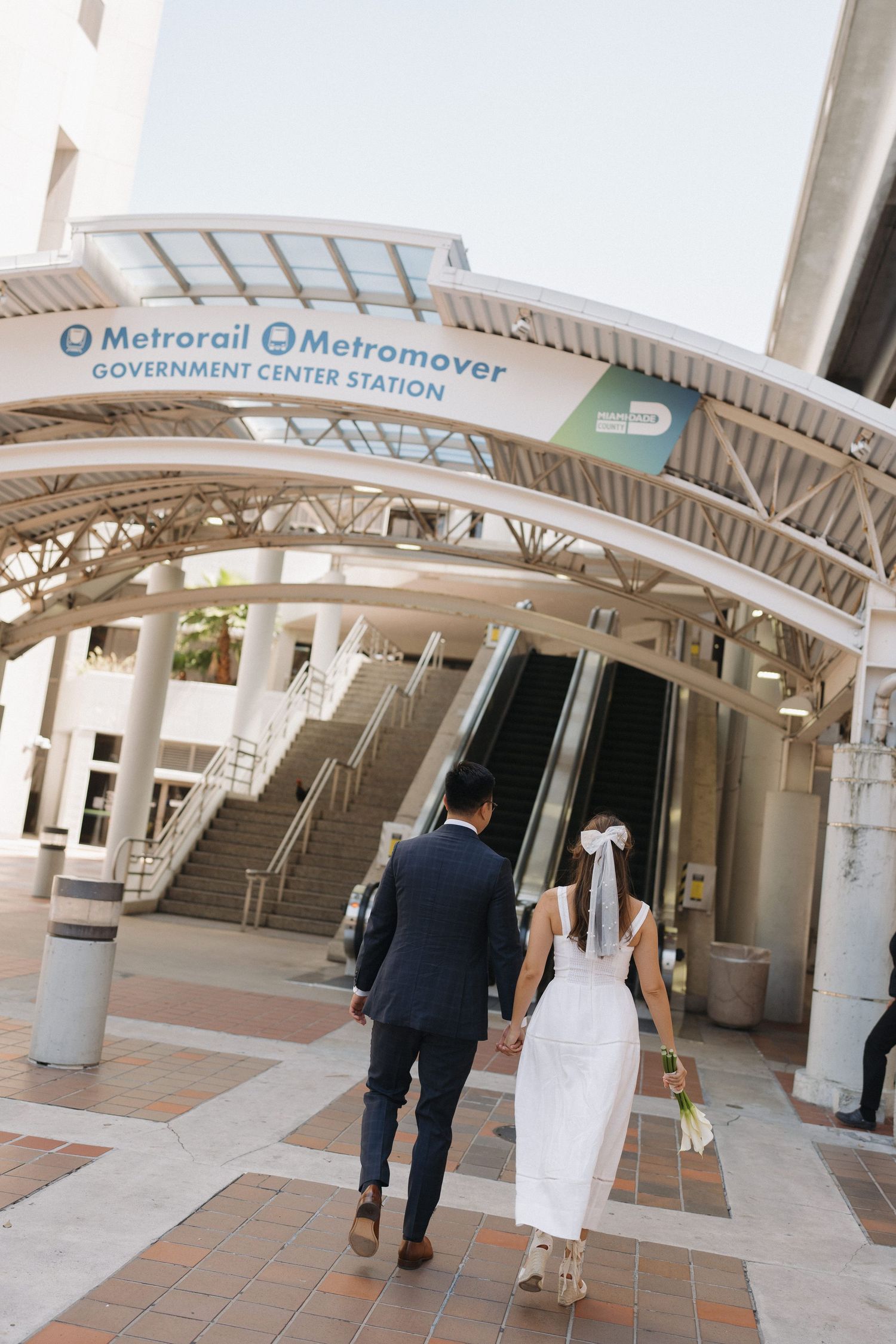 Wedding couple walking through modern transit station with curved architectural details.