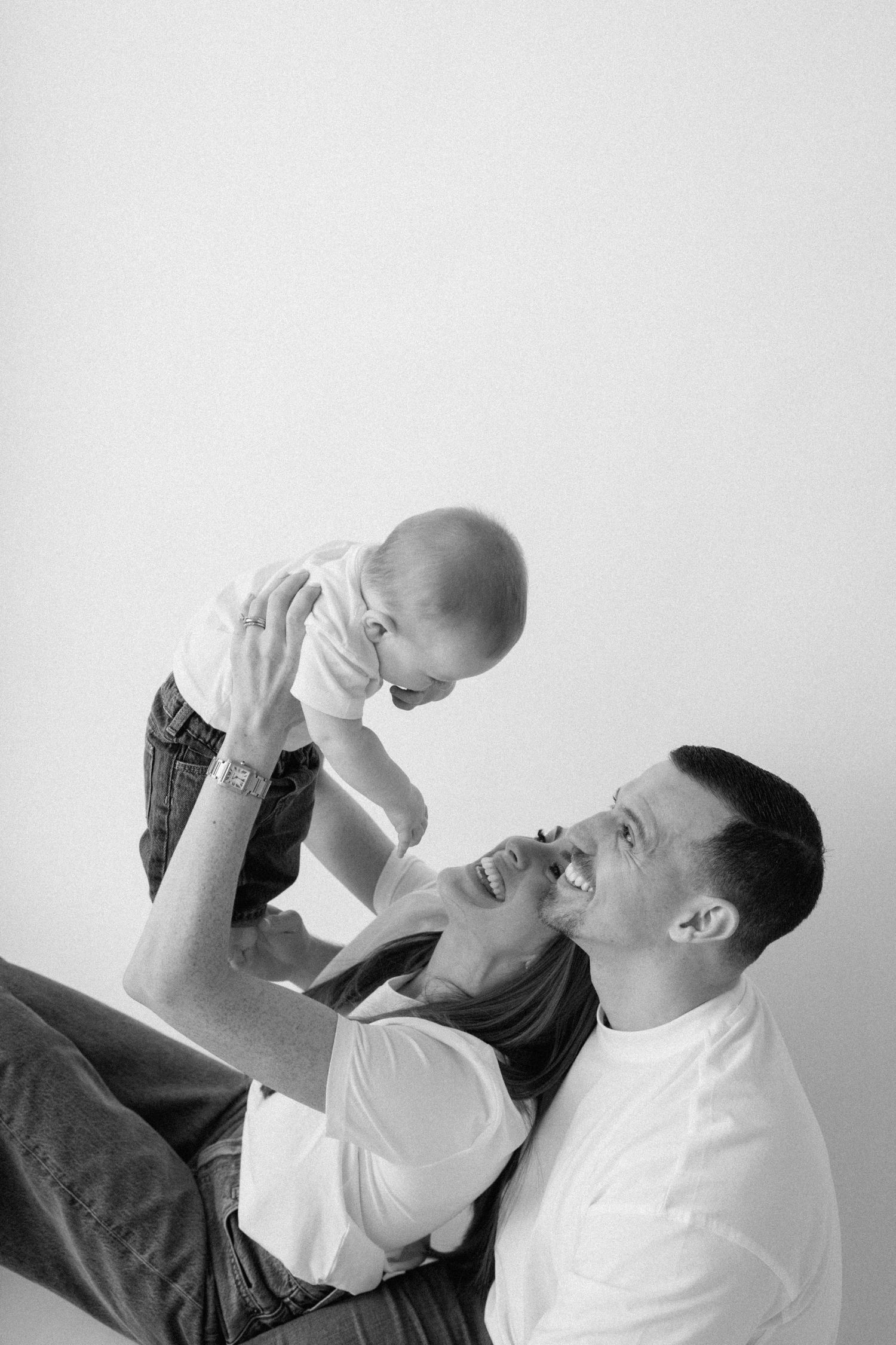 Black and white portrait of parents playing with baby.