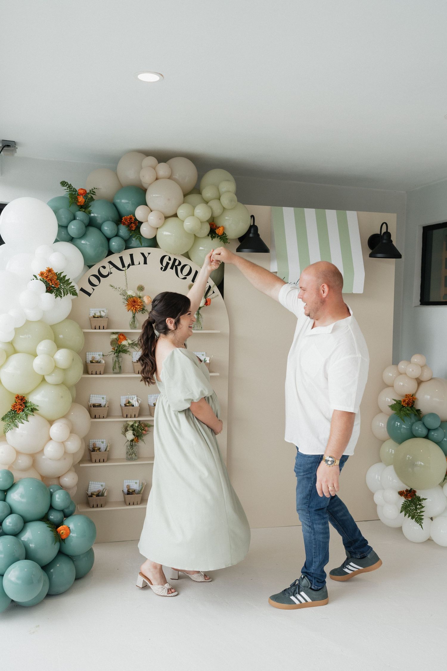Festive baby shower setup with mint and cream balloon arch and floral decorations.