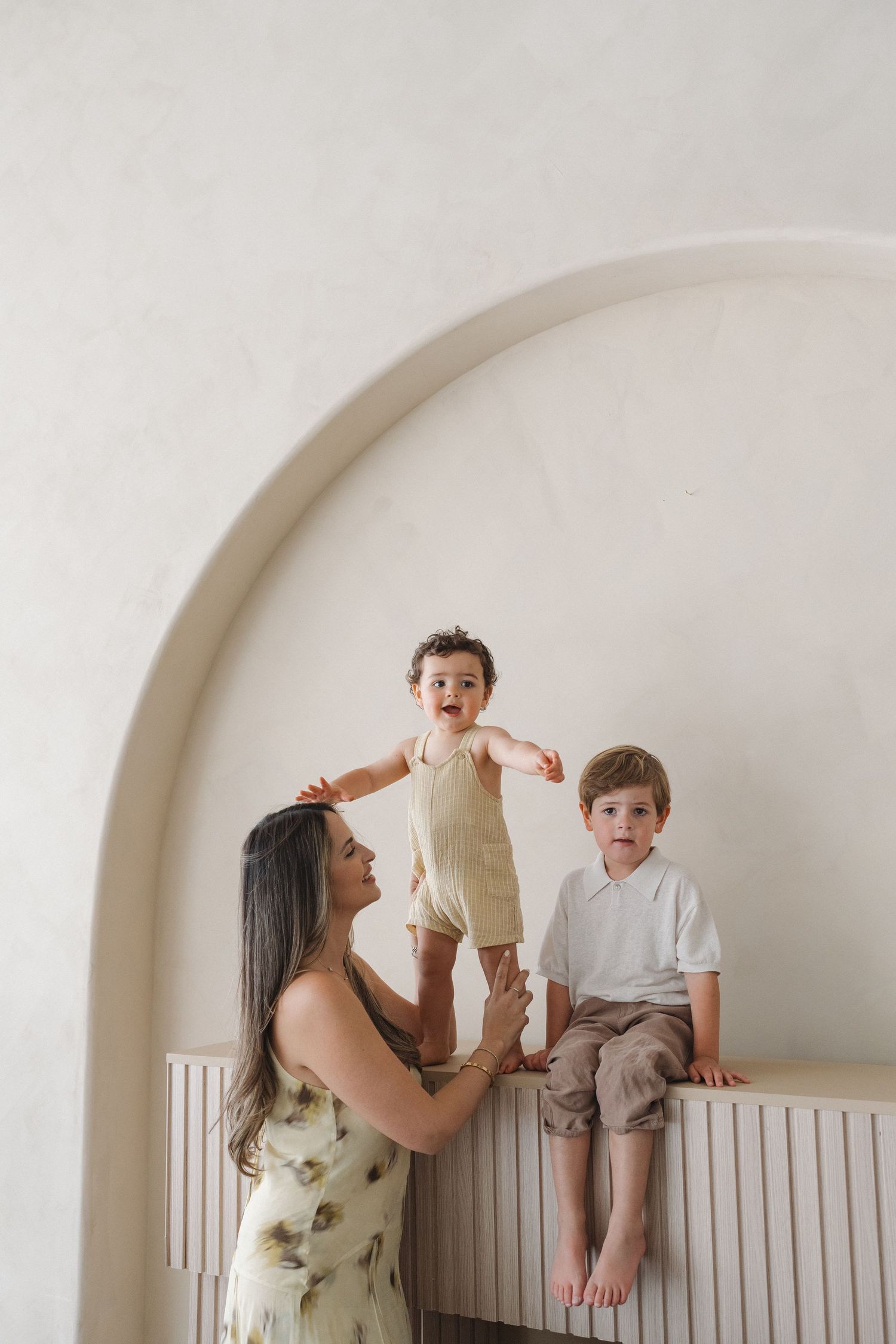 Joyful family interaction against white wall with arched detail.