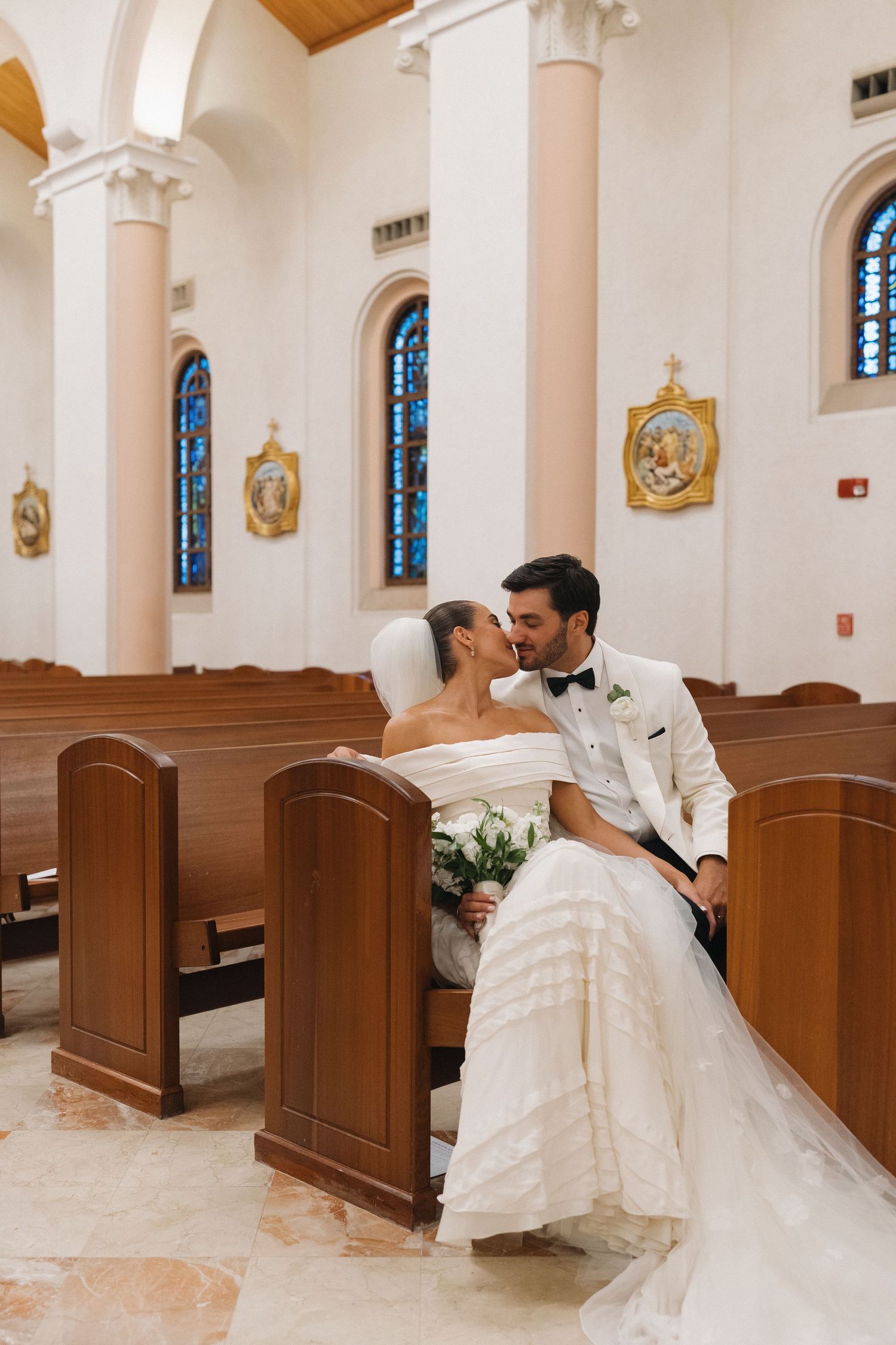 Intimate moment shared in church pews after wedding ceremony.