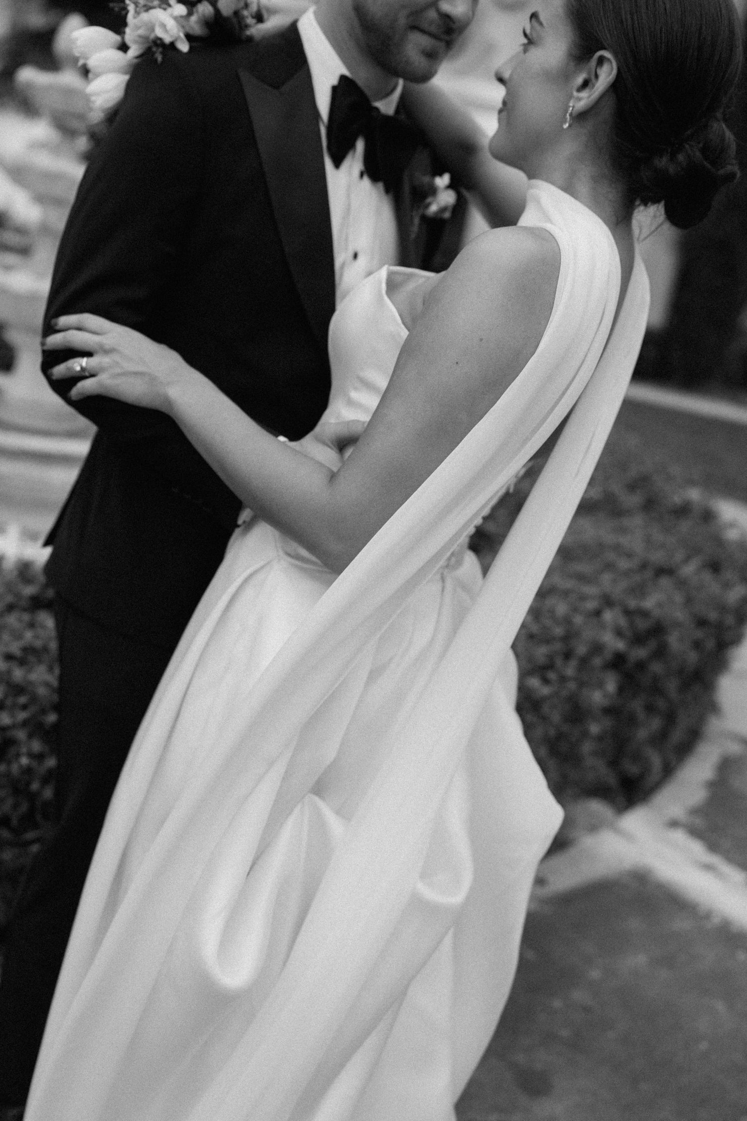 Elegant black and white wedding portrait showcasing bride's flowing dress and romantic embrace.