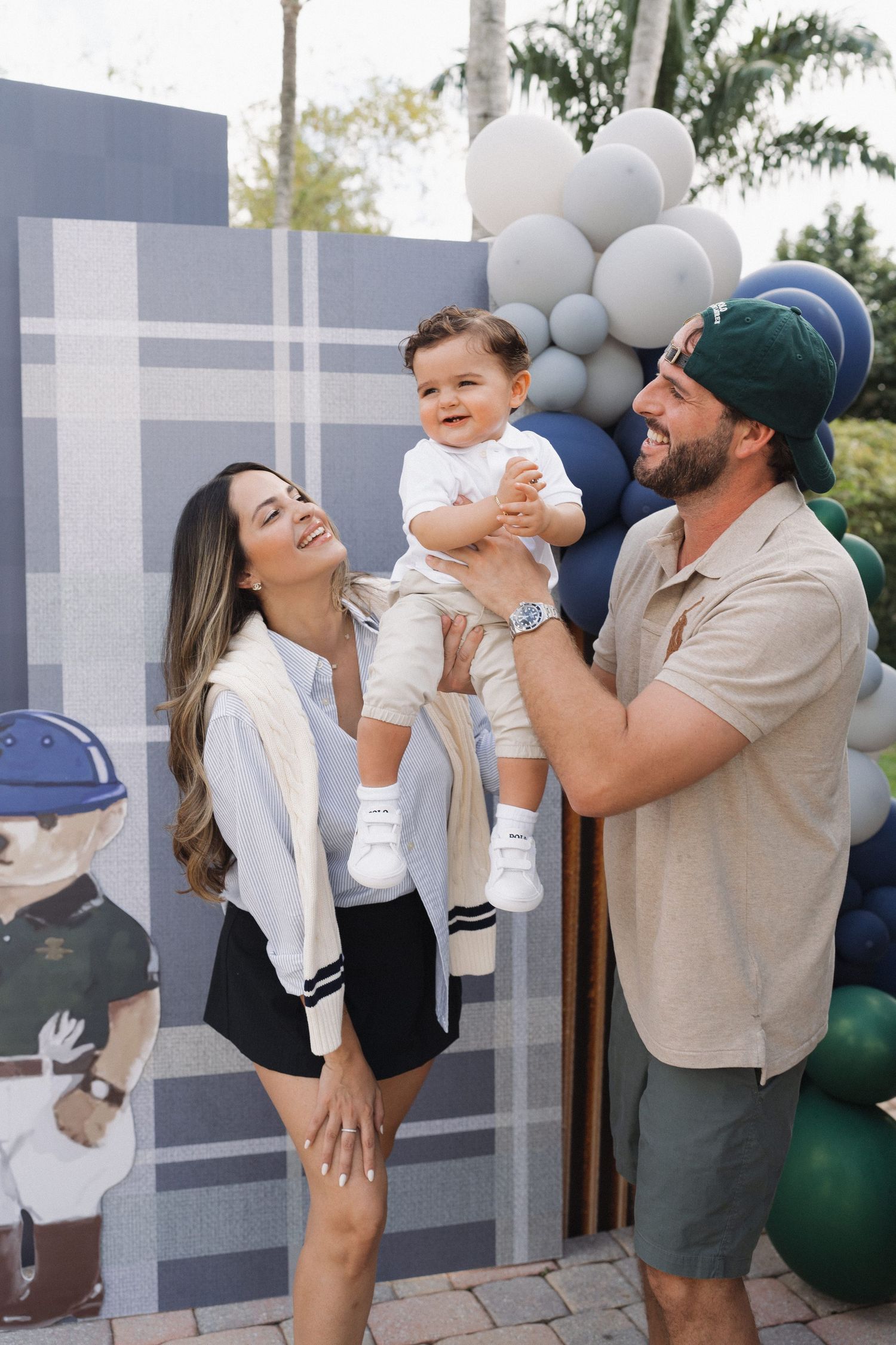 Candid family moments captured against blue and white balloon backdrop.