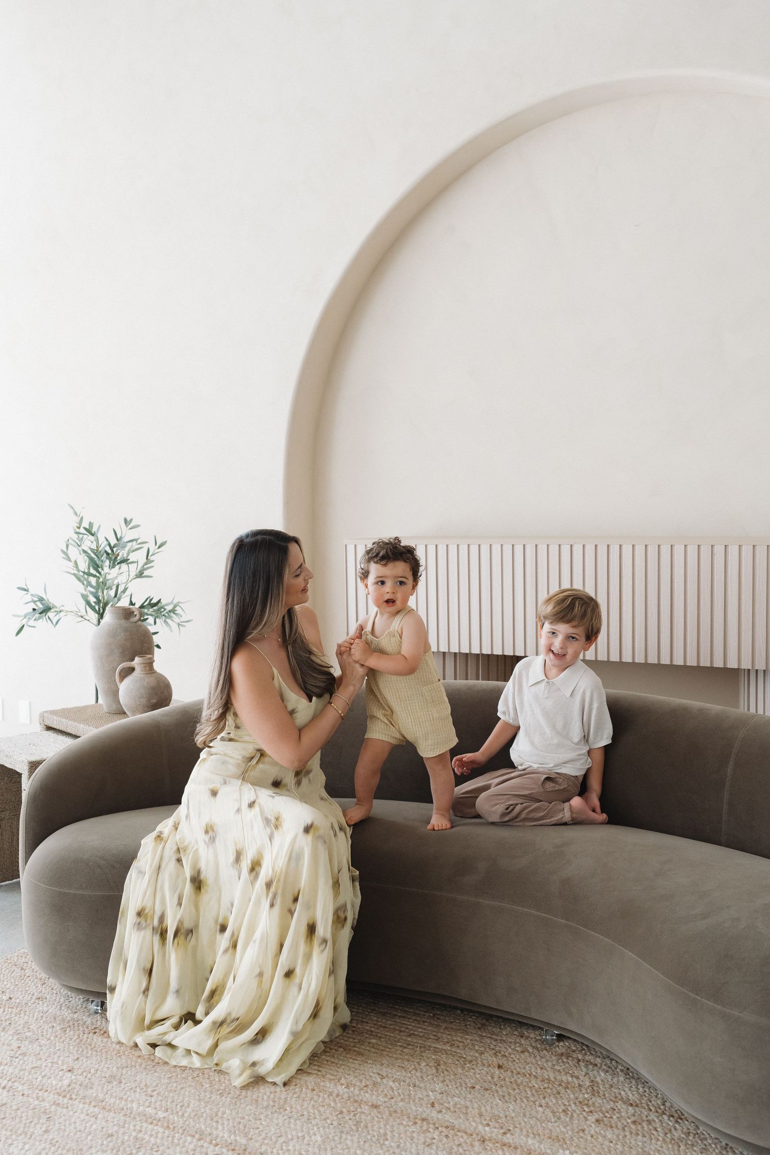 Modern living room scene with curved sofa and arched wall details.