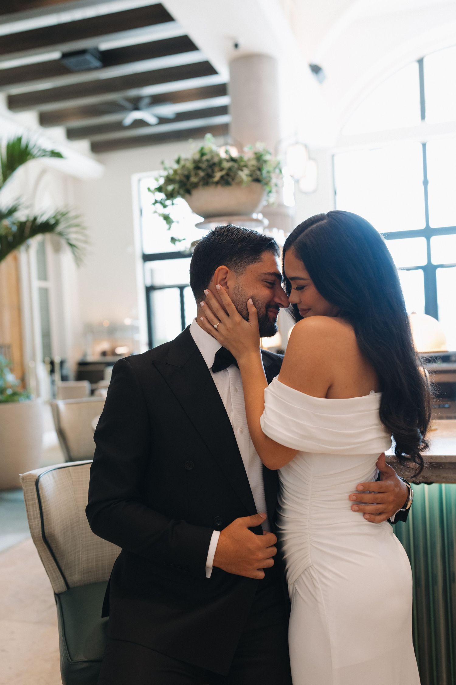 An intimate moment between a couple in formal attire in an elegant indoor setting.