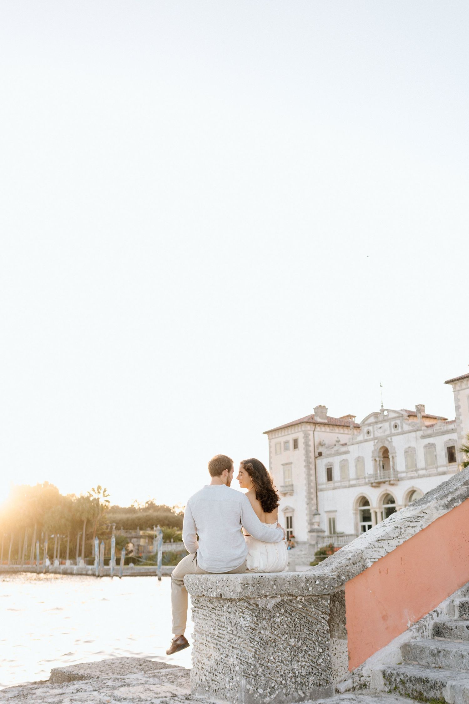 A romantic sunset scene at a coastal mansion with white Mediterranean architecture.