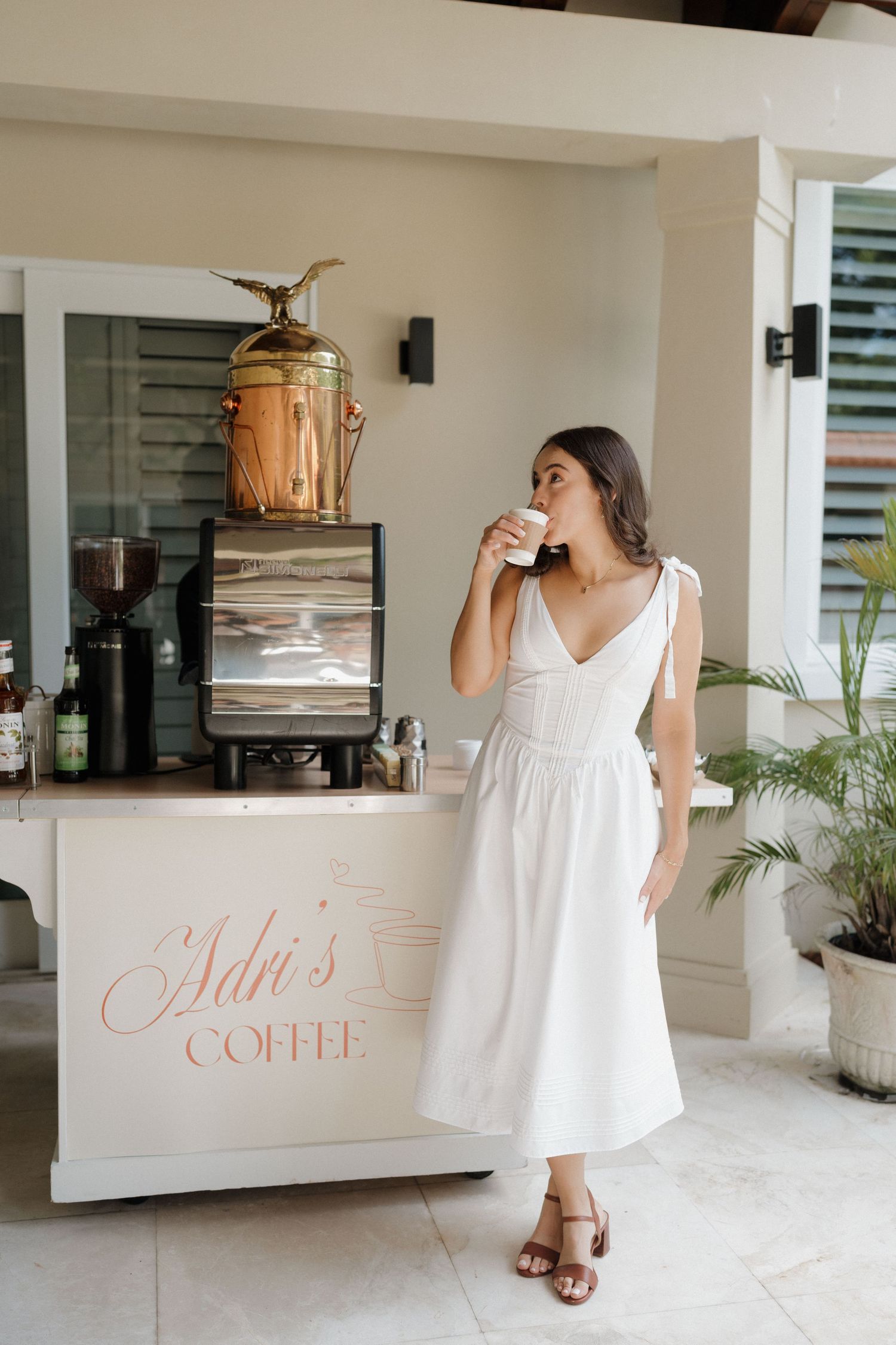 Outdoor cafe setting with white decor and Ada's Coffee sign visible.