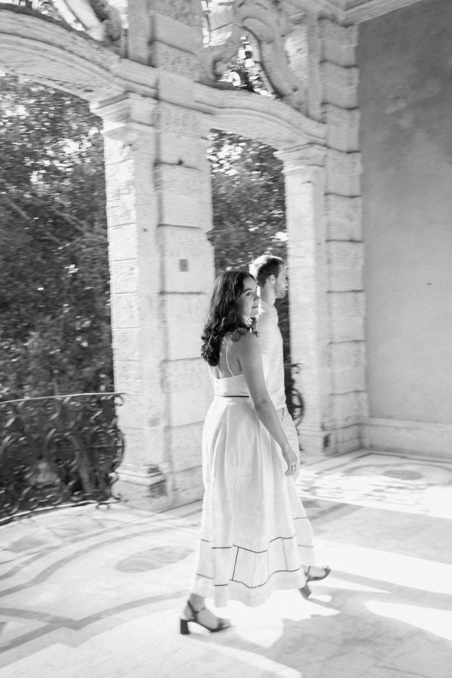 A series of romantic moments captured under white stone archways and columns.