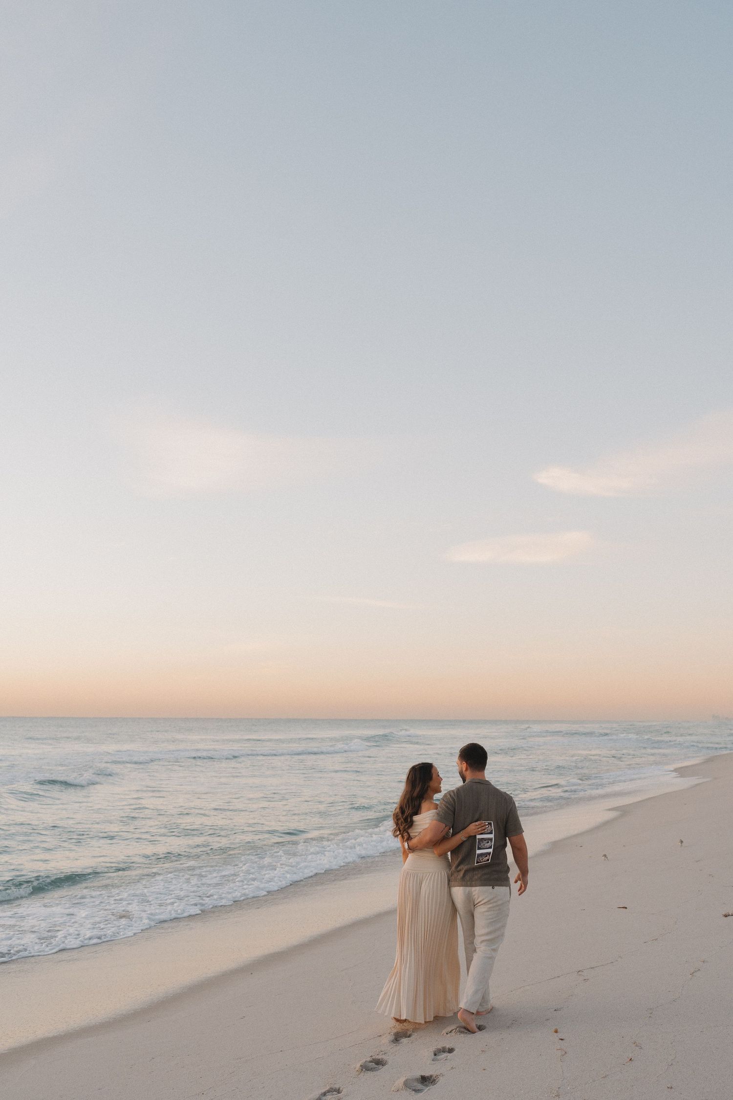 A serene beach scene at golden hour with soft pastel colors reflecting on the sand.