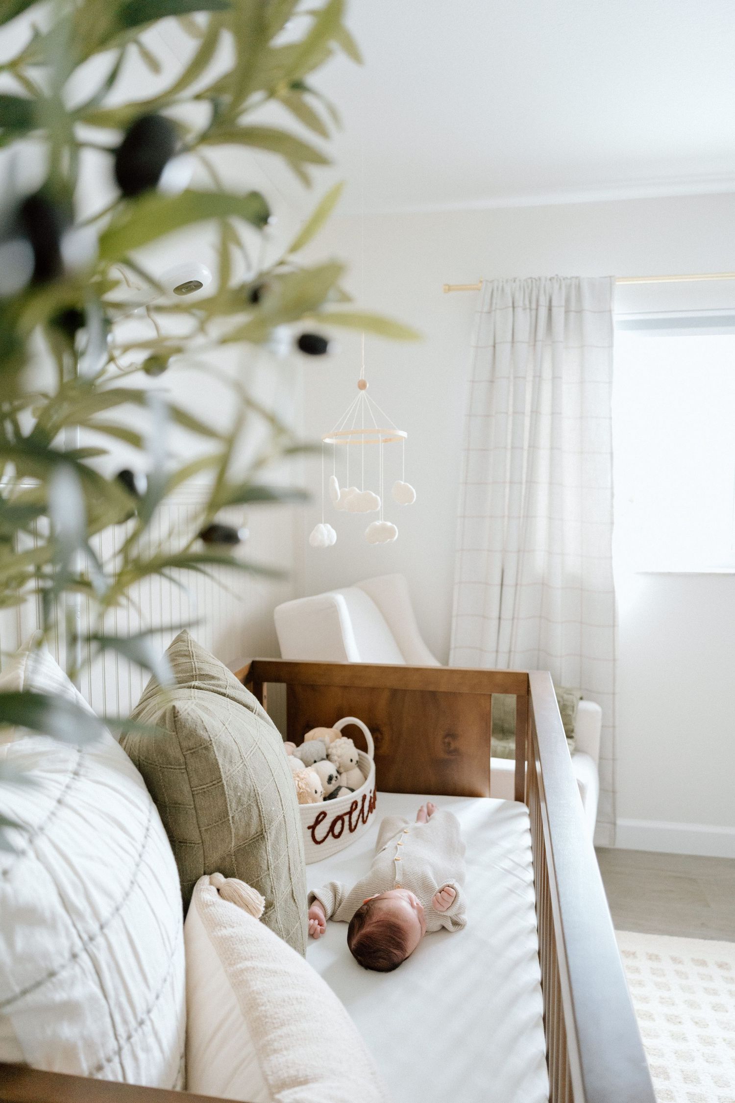 White nursery interior with crib and natural light streaming through windows.