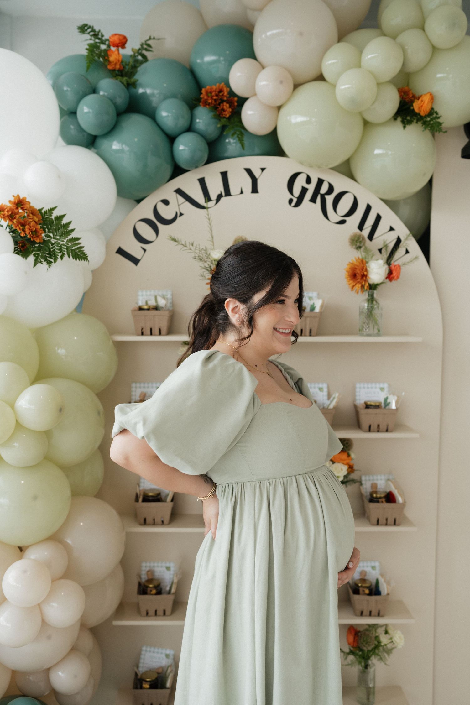 Event space decorated with mint green and cream balloon garland under 'Locally Grown' sign.